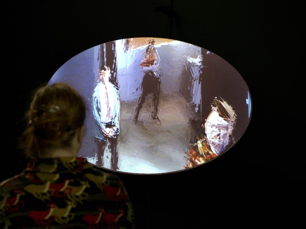 A digital mirror comprised of a wall-mounted wood oval, webcam, computer software and projector. When a viewer appears in front of the oval and camera, their image is projected in real-time on the oval. A viewer's image is modified by live brushstroke animations that respond to movement and variable light.