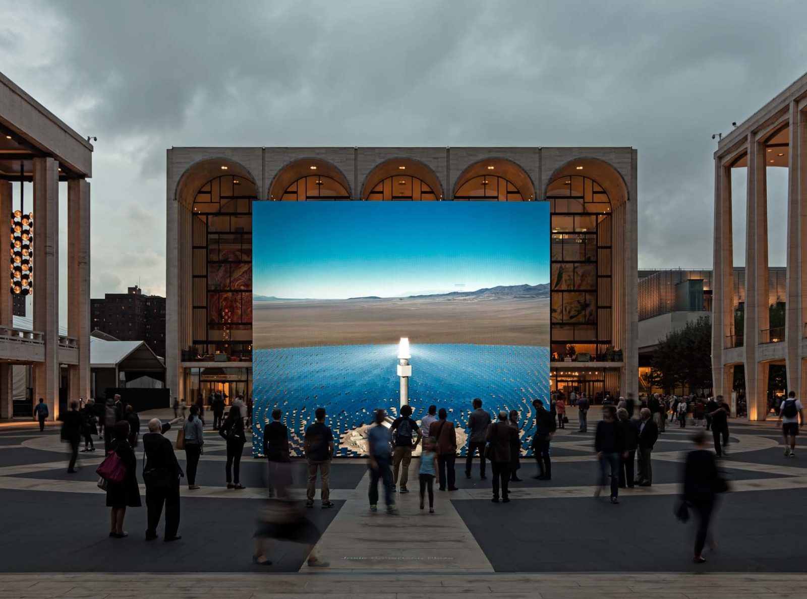 A large-scale digital art installation installed in a public plaza with a crowd of people in front.