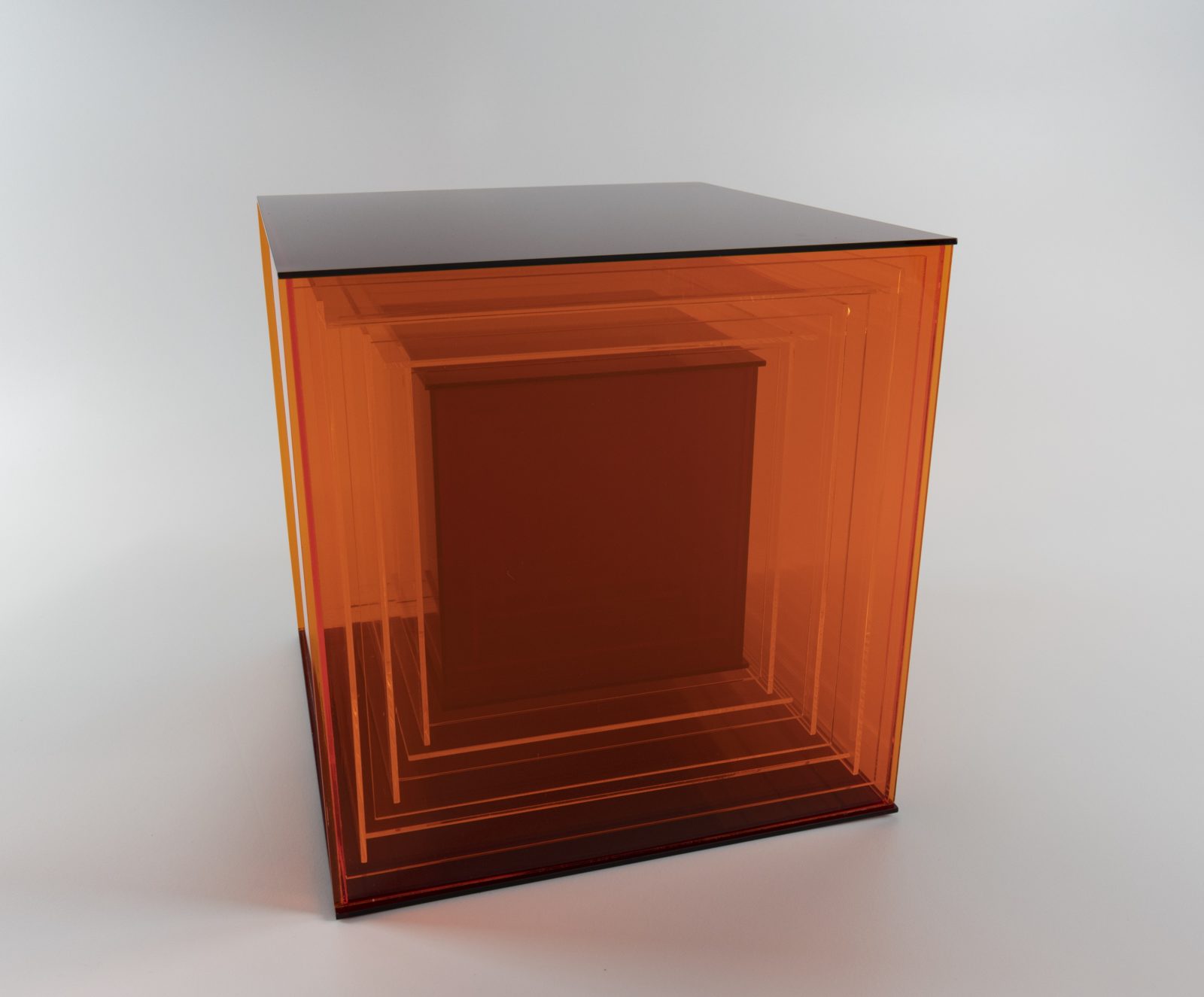 A sculpture of orange and red Plexiglas panels on a grey background.