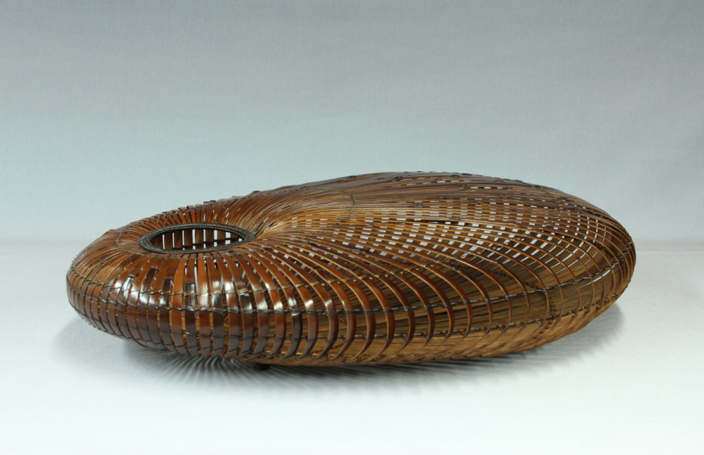 A bamboo vessel made of madake bamboo and rattan on a grey background.