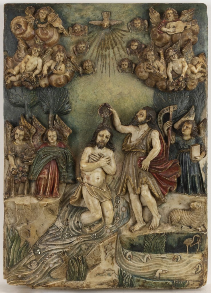 A bas-relief and painted carving depicting the baptism of Christ by St. John the Baptist in a running stream. Above them are a choir of angels.
