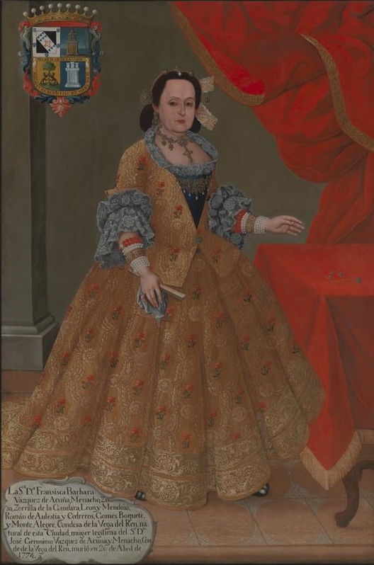 A painting depicting a woman in an opulent brocade dress in front of a table and wall draped in red fabric. Her coat of arms is at the top left corner and a cartouche with her biography is in the bottom left.