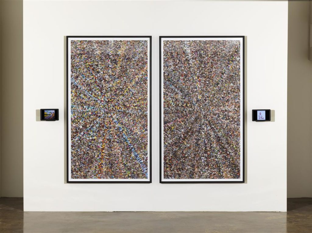 Two small monitors hang alongside two large collages on a wall